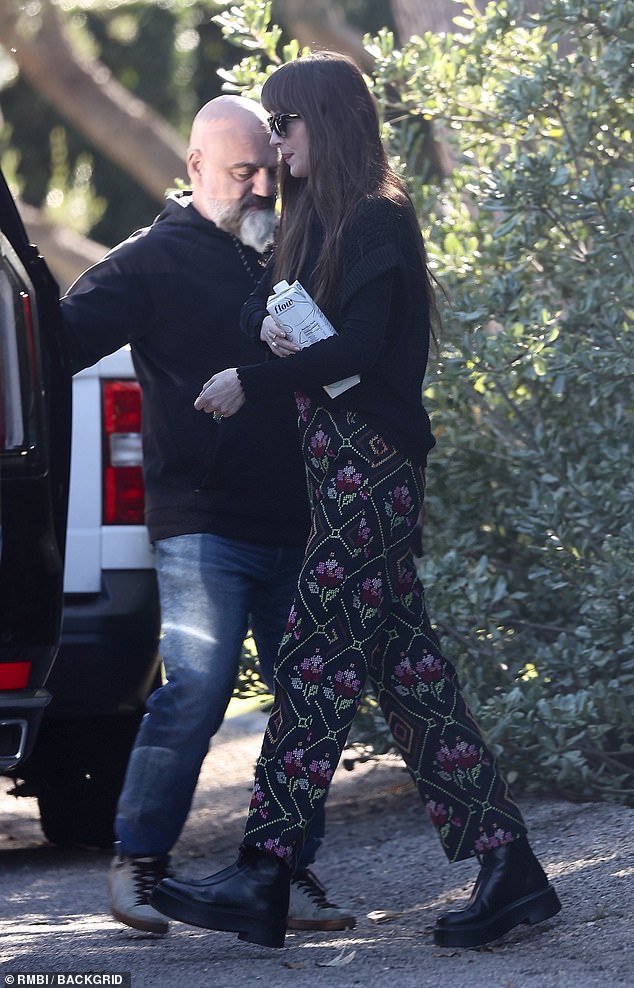 She also wore a black sweater over a matching top, along with chunky black leather boots, and her brunette locks were styled long and straight to mid-back with her signature bangs.