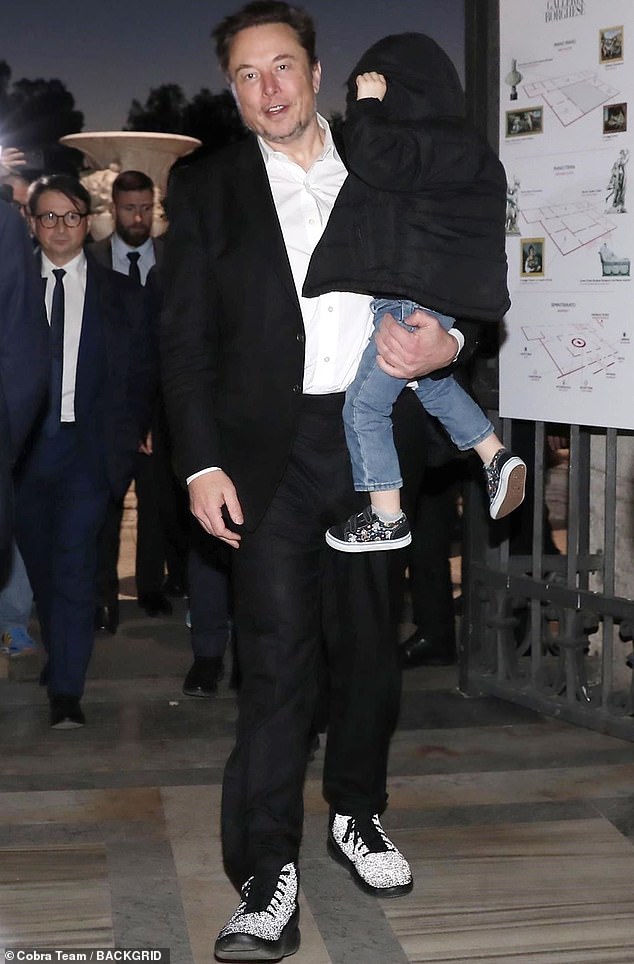 Musk and 'Lil X' as the toddler covers his face with the hood of his black jacket and his father looks into the camera