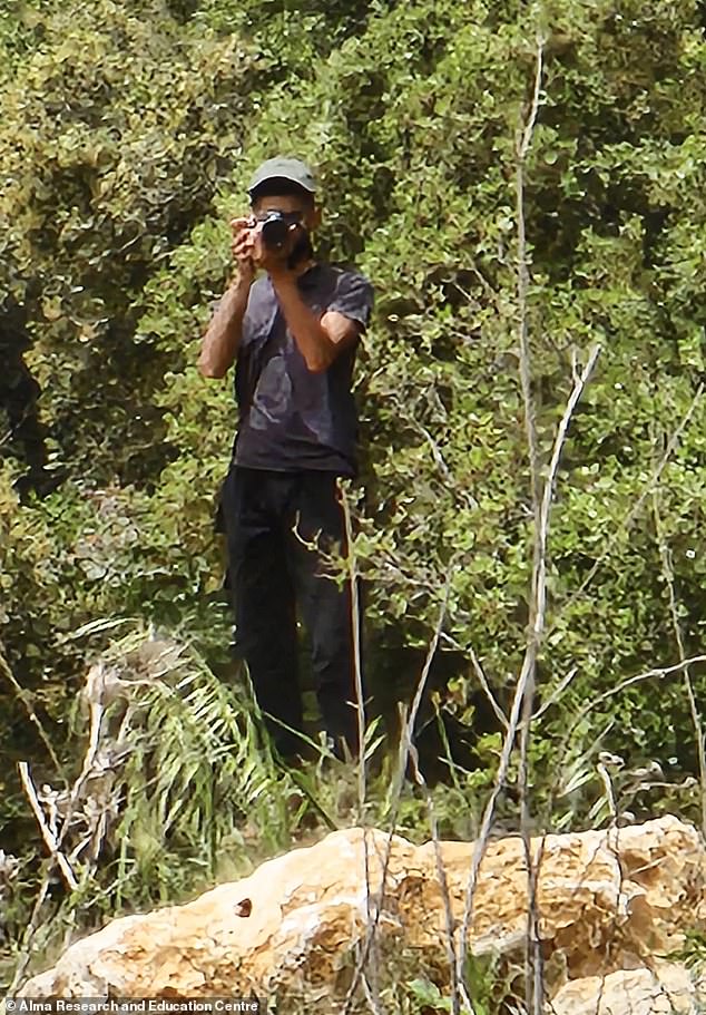 A man with a camera collects information from Lebanon at a location near the border with Israel