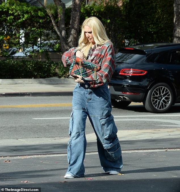 The 54-year-old singer pulled her red and green plaid blouse above her waist and wore a matching plaid bag, baggy blue cargo jeans and white cowboy boots.