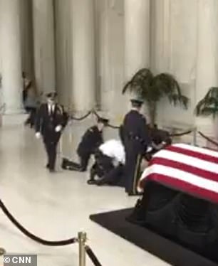 Other officers run to the side of the collapsed honor guard member