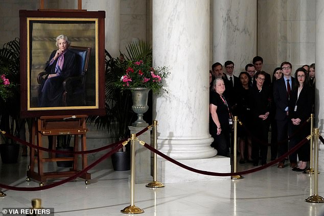 People listen to the private ceremony for O'Connor at a 1999 portrait of the first female Supreme Court justice, displayed as her casket lies at rest in the Supreme Court's Great Hall