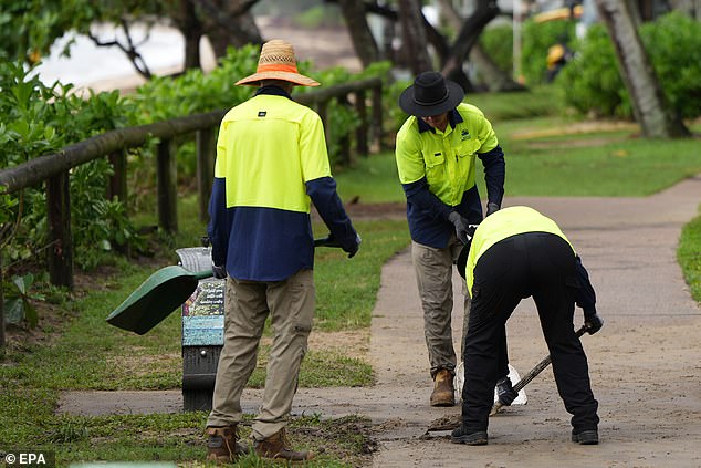 Workers clean up after flooding in the Cairns suburb of Palm Cove