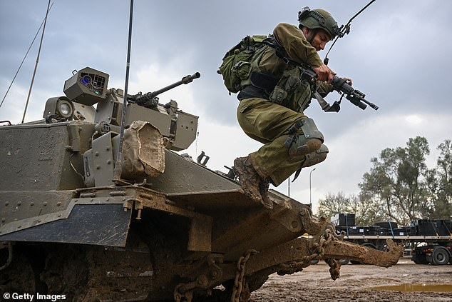 A reservist jumps from an armored personnel carrier at a staging post near the Gaza border