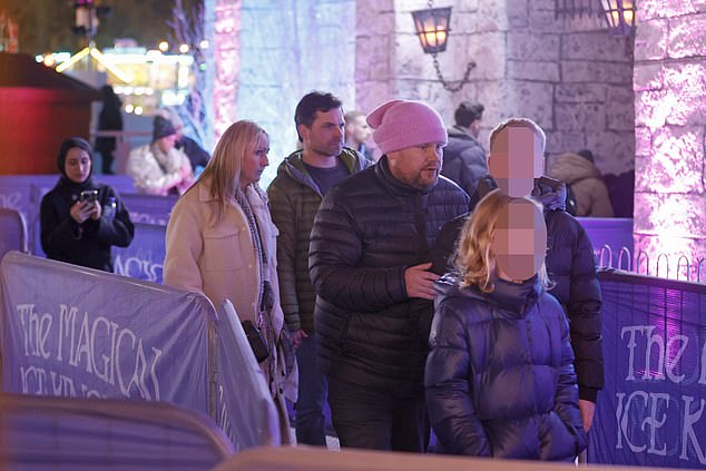 To keep out the winter cold, James wrapped himself warm in a black padded jacket and a pink hat