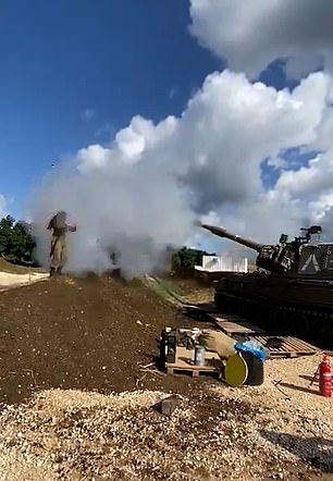 The young woman stands in front of the self-propelled howitzer as it fires a bullet