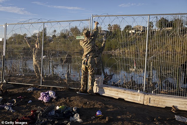 A member of the Texas National Guard sets up a temporary fence on the banks of the Rio Grande River in Eagle Pass, Texas, on Tuesday after another record-high single-day crossing of 12,600 apprehensions