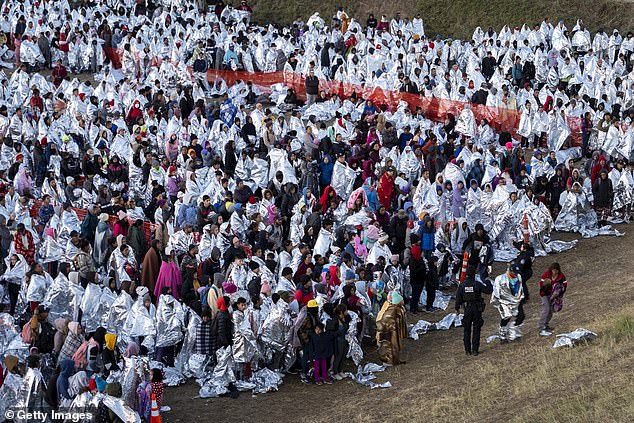 An aerial view of thousands of migrants, most wearing thermal blankets, awaiting processing at a U.S. Border Patrol transit center in Eagle Pass, Texas