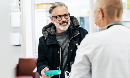 A cheerful customer being served at his local pharmacy and picking up his prescription