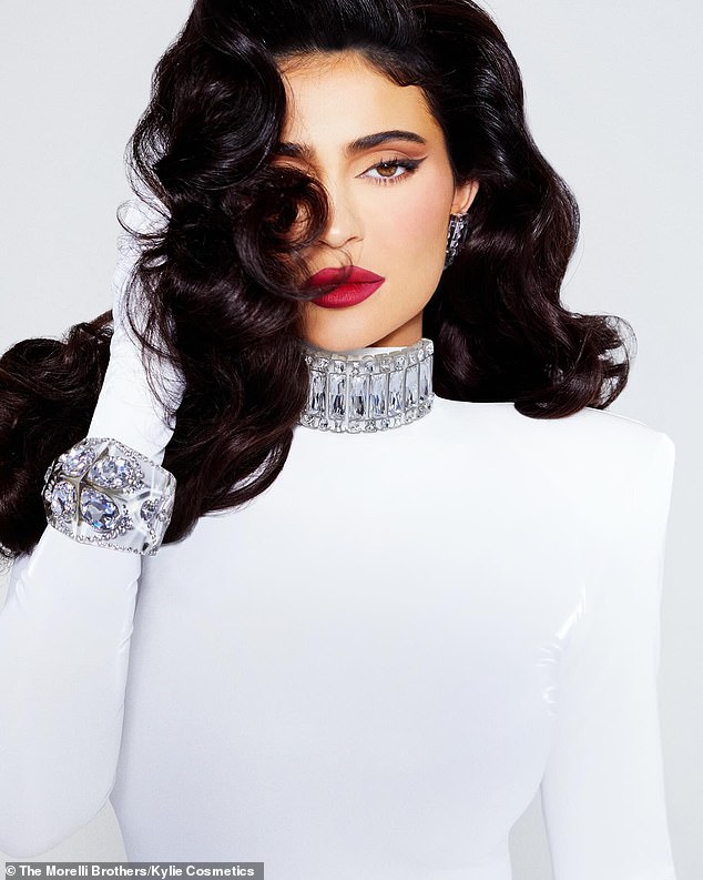 Outfit change: A third photo of Jenner showed her in an elegant white dress with a beaded collar and cuffs, red lipstick and her signature raven locks styled in voluminous curls