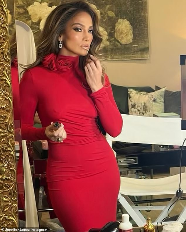 The actress/singer, 54, wowed in a figure-hugging red dress as she applied lip gloss in a mirror