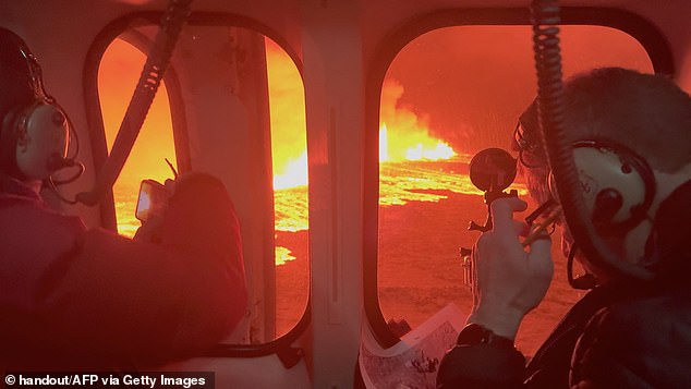 Emergency workers and scientists in an Icelandic Coast Guard helicopter fly over a volcanic eruption