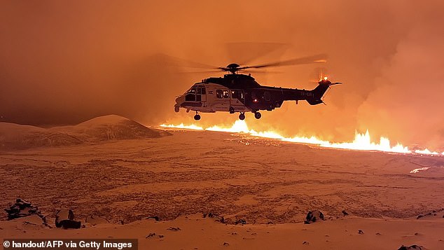 An Icelandic Coast Guard helicopter flies over a volcanic eruption on the Reykjanes Peninsula