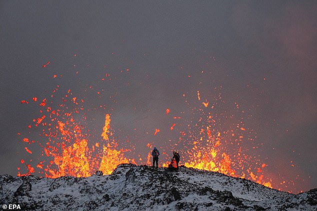 A team of scientists work at the edge of a volcanic fissure as lava spews during a volcanic eruption, near the town of Grindavik, on the Reykjanes Peninsula