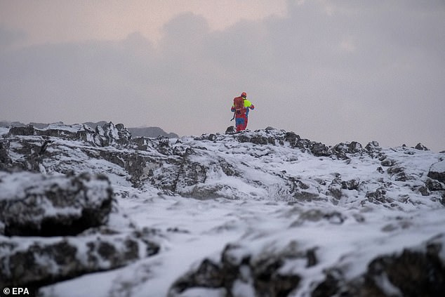 A rescuer walks in an area near a volcanic eruption, near the town of Grindavik