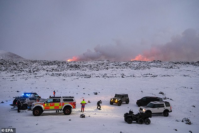 Members of a rescue team gather in an area close to a volcanic eruption