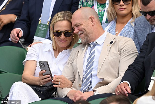 Zara Phillips and Mike Tindall smile as they look at her phone during Day Two of Wimbledon last year