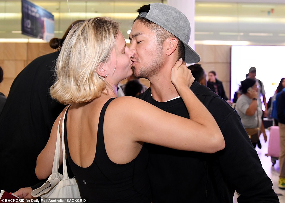 A couple reunites at Sydney airport after weeks apart