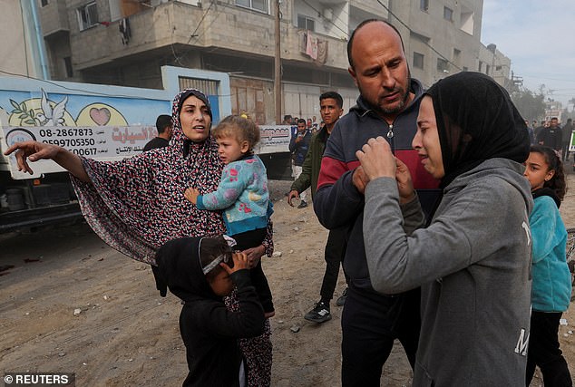 A woman and children react as Palestinians gather at the scene of an Israeli attack on a house amid the ongoing conflict