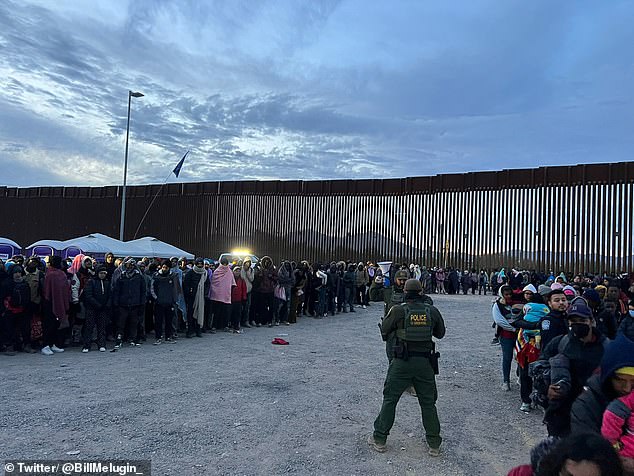 A long line snakes across the gravel at the processing center in Lukeville after hundreds of migrants cross the border