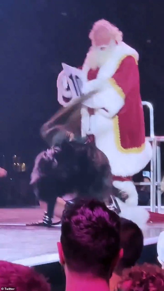 The 65-year-old singer briefly sat on the edge of a second chair next to Santa before standing up and holding up signs