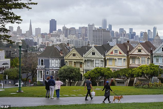 People in Alamo Square looked out at 'The Painted Ladies' row of Victorian houses amid a rainstorm in San Francisco on Tuesday