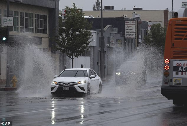 A vehicle splashes through puddles along a street that begins to flood in the Van Nuys section of Los Angeles as Tropical Storm Hillary made landfall in Southern California