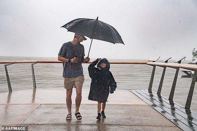 A BOM spokesperson said the weather system will hit Brisbane with at least 70mm within the hour.  A father and son walk in the rain