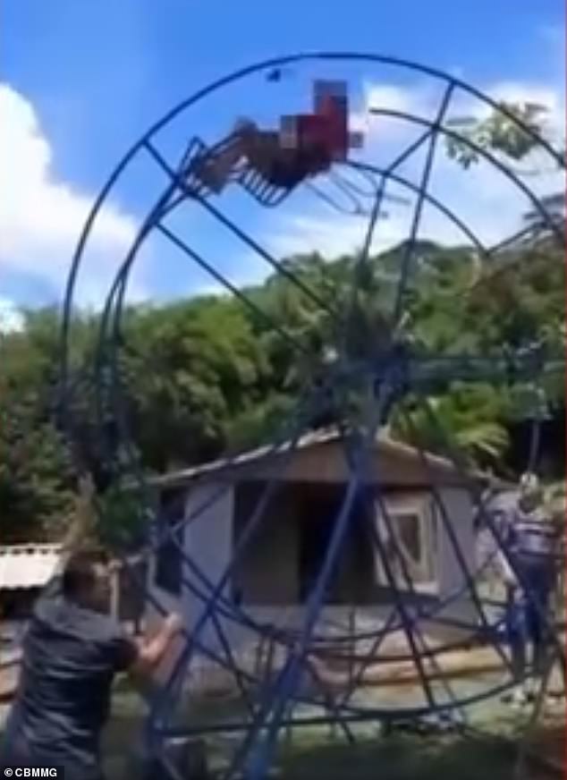 Maria do Carmo is seen sitting on a metal bench at the top of the Ferris wheel before a man (bottom left) spun the fairground ride, which was designed for children between 5 and 10 years old.