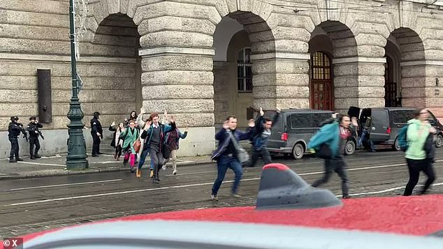 People are seen running from a building in Prague with their arms in the air as police arrived on the scene