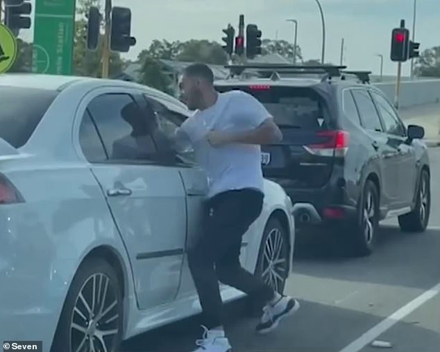 Dashcam footage captured a man (pictured) wearing a white T-shirt, dark trousers and trainers throwing punch after punch after punch through the open window of a white sedan