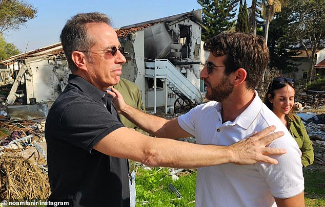 Seinfeld lays his hands on a community member to show his support during his trip to Israel this week, as he and his wife paid their respects to the families whose loved ones were murdered