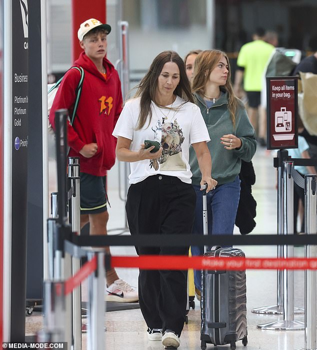 Former model Bec looked relaxed in a white graphic T-shirt with a detailed design on the front and loose-fitting black trousers