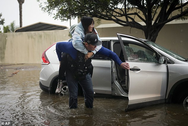 Detective Bryce Ford of the Santa Barbara Police Department helps a motorist out of her car on a flooded street during a rainstorm