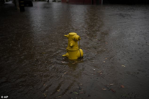 A fire hydrant is partially submerged on a flooded street