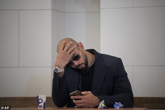 Andrew Tate checks his mobile phone in the Court of Appeal building in Bucharest, Romania, Friday, December 22, 2023