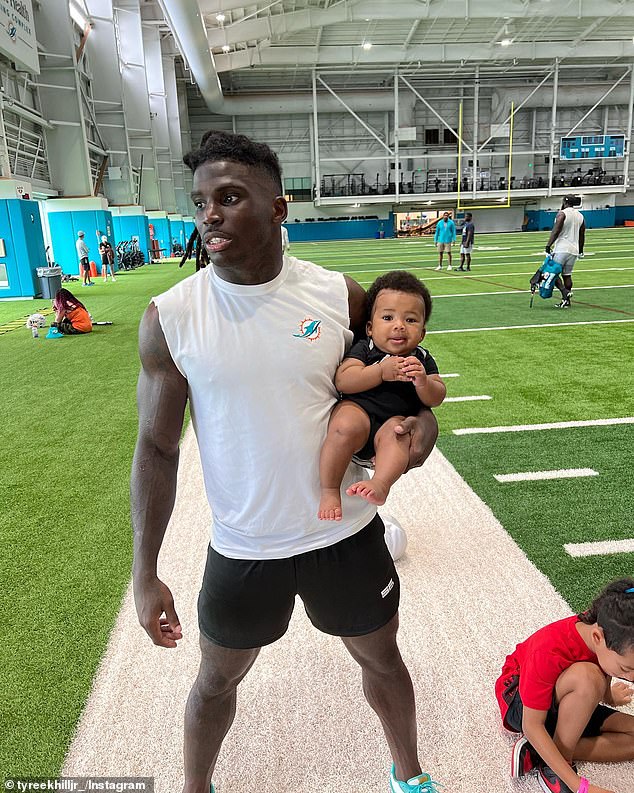 A photo posted in August shows Hill Tyreek Jr.  under one arm during dolphin training