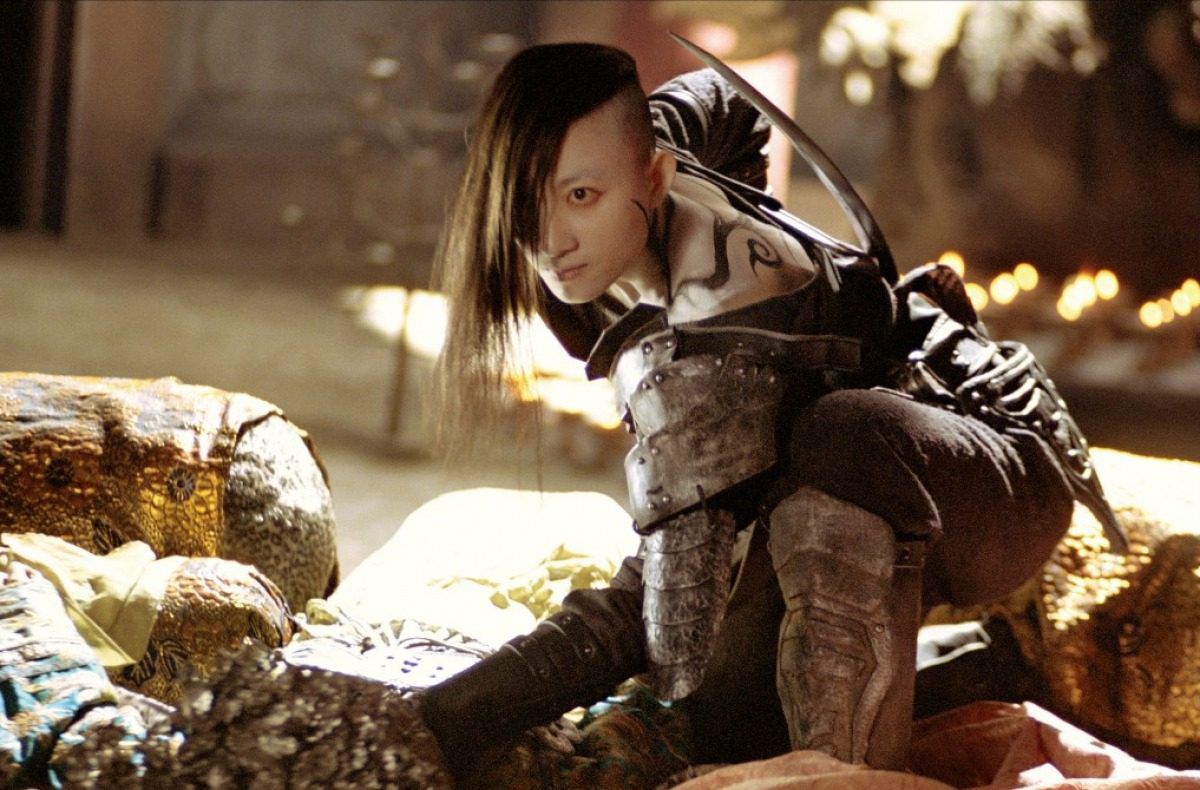 A tough-looking villain in Seven Swords, with tattoos and a shaved side of her head, crouches down and wears armor.