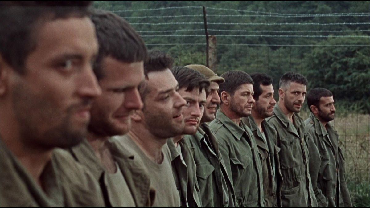 A close-up of several soldiers lining up next to a barbed wire fence in The Dirty Dozen.