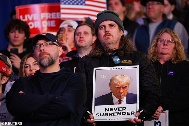 person holds a sign with the mugshot of Republican presidential candidate and former US President Donald Trump, during a Trump rally in Durham, New Hampshire