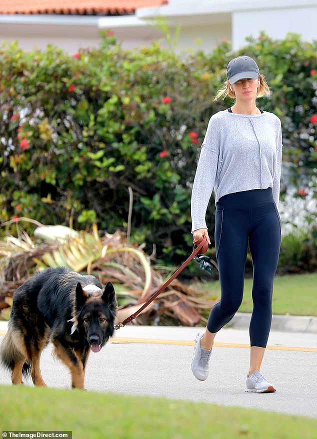 She wore a flowing gray shirt with cropped midnight blue leggings and white sneakers, along with a distressed gray baseball cap and Apple AirPods for some entertainment.