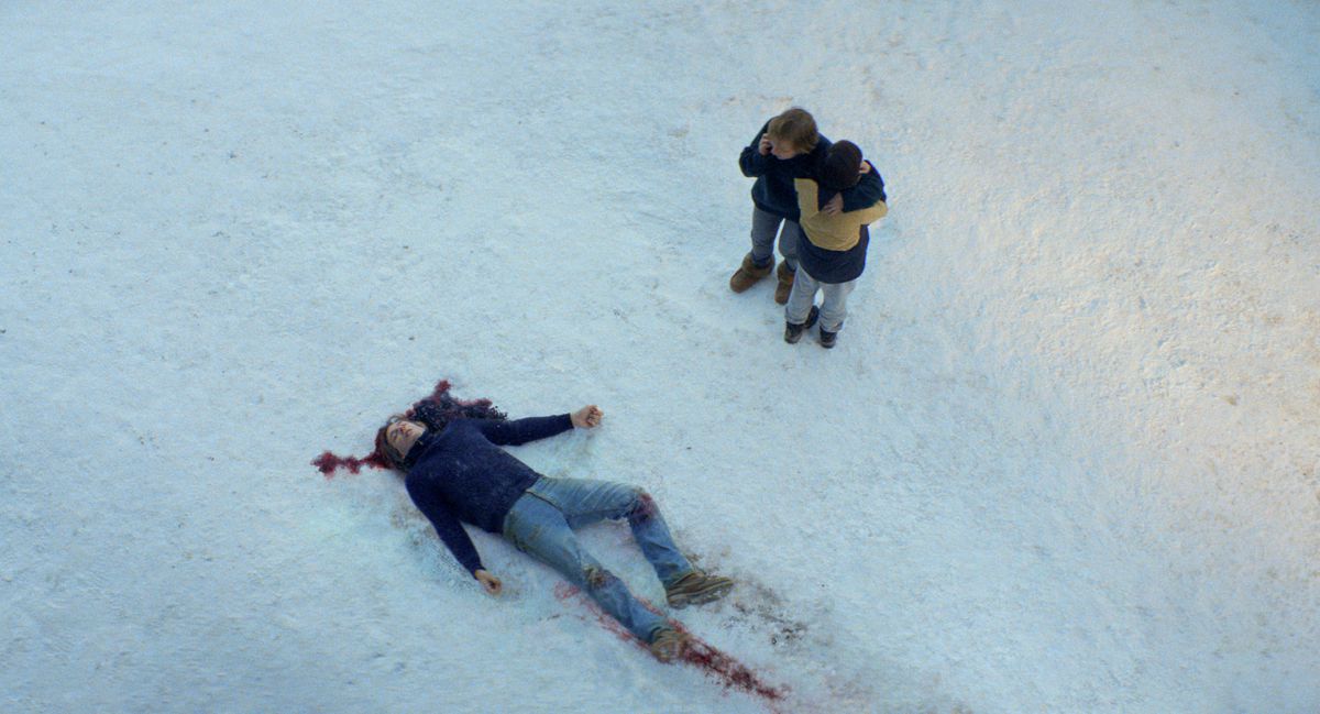 A dead, bloody body in the snow in Anatomy of a Fall, while someone is on the phone nearby