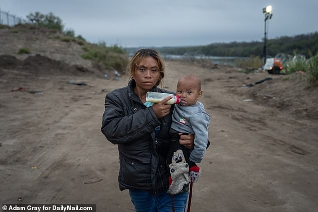 Honduran migrant Arile Nunez, 25, bottle-feeds her son Edwin, 8 months, as they walk along the bank of the Rio Grande River after crossing the border from Mexico into Eagle Pass, Texas