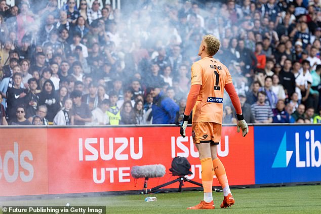 Melbourne City's Thomas Glover clears away a flare thrown onto the pitch during last year's A-League chaos at AAMI Park