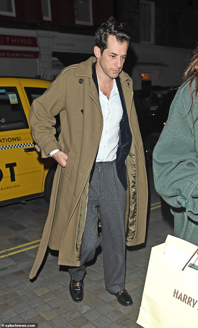 Mark stepped out in gray wide-leg trousers, with a white open-collar shirt tucked into the waistband, while wearing a khaki macaron.