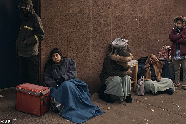 Migrants line up in the cold as they look for shelter outside a migrant assistance center in New York