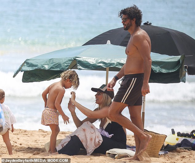 They finally found a place to make camp, laid out a large beach towel and set up a green umbrella to protect them from Australia's bright summer sun.