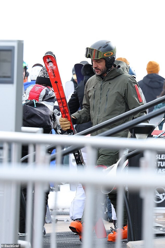 Her estranged husband, dressed in an olive green jacket and matching ski goggles