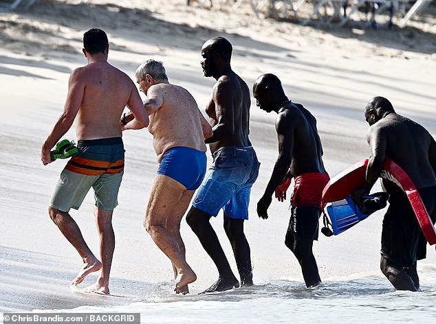After entering the water, a group of men helped him back to his lounger, where the billionaire could continue to relax