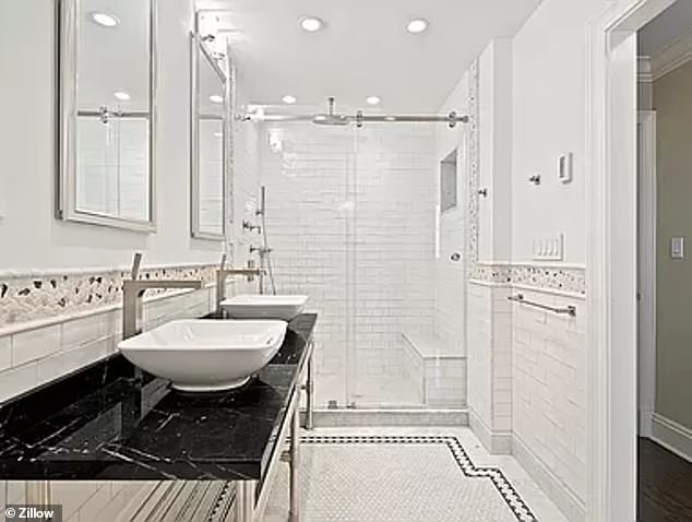 One of the spacious bathrooms has double sinks and a shower with white tiles and a bench